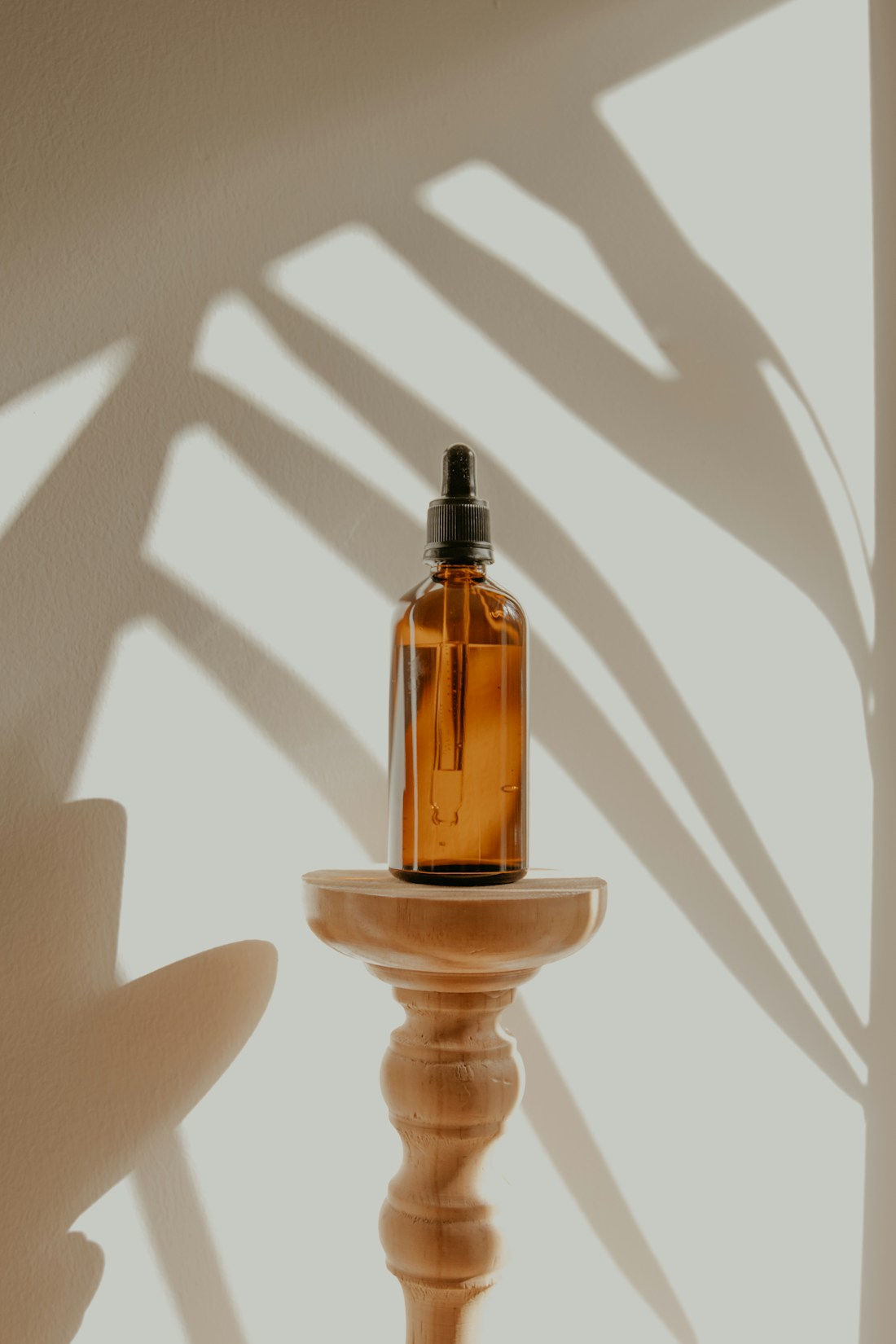 Botanical shadows surrounding an amber oil bottle